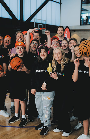 A group of participants and support workers enjoying a basketball activity